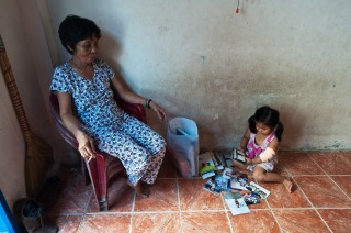 Bùi Thị Bé watches as her great granddaughter looks through a pile of family photos.